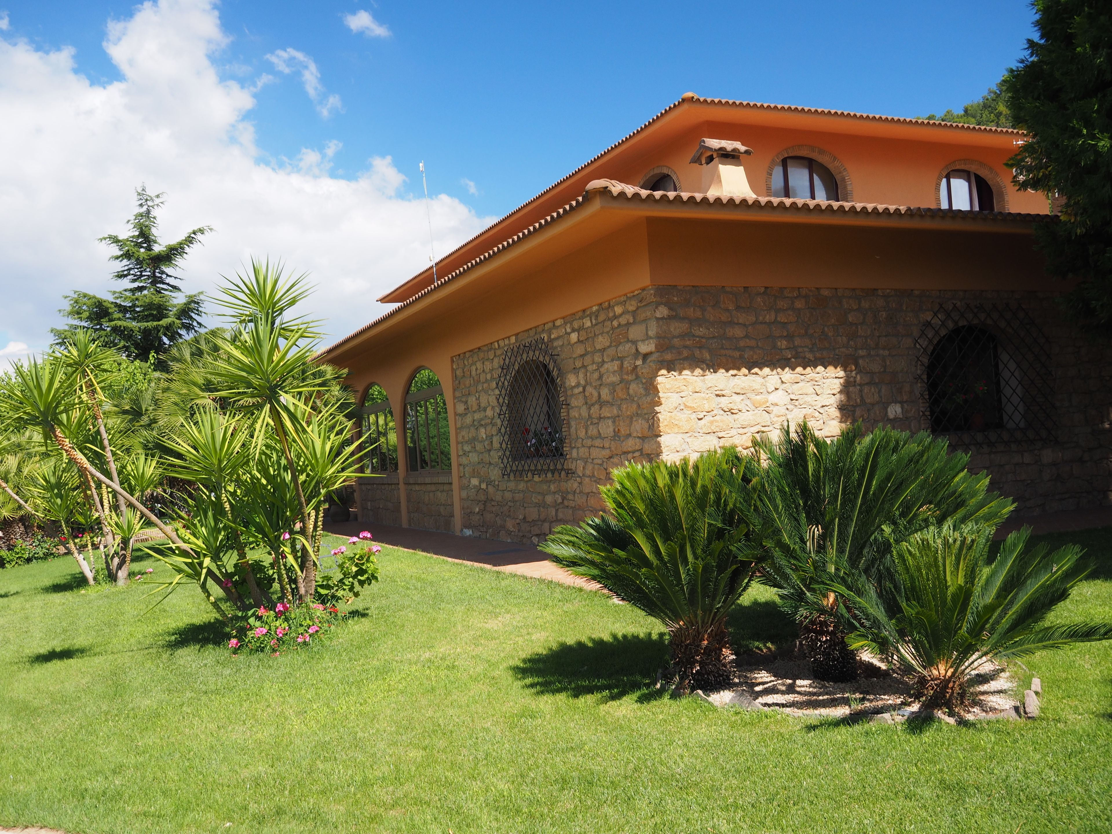 A two-story house with a stone facade, arched windows, and a tiled roof.
