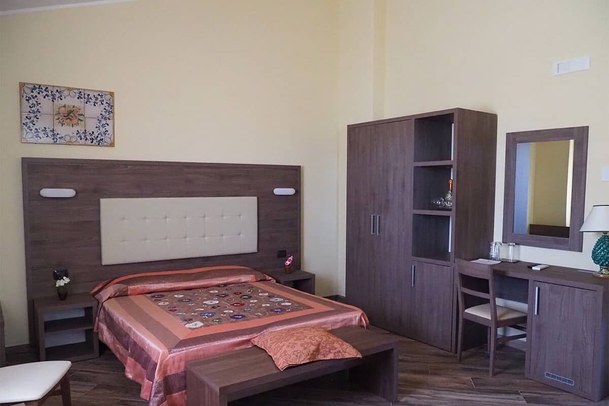 Une chambre à coucher avec un lit, un bureau, une armoire et un miroir.