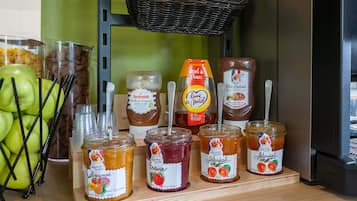 Una exhibición de diversos alimentos, como manzanas, frascos de mermelada y una cesta de pan.