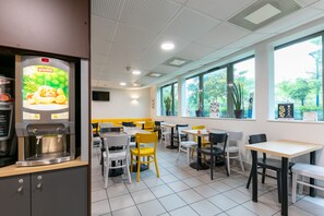 Ein modernes Café mit Kaffeemaschine, Sitzgelegenheiten und großen Fenstern.
