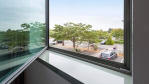 A view from a window overlooking a parking lot with trees and a clear sky. - B&B HOTEL Toulouse Basso Cambo (Toulouse)