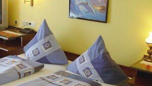 Una habitación de hotel con dos camas, televisión, escritorio y lámpara.