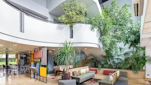 A spacious lobby with a curved ceiling, multiple seating areas, and indoor plants. - B&B HOTEL Lyon Centre Part-Dieu Gambetta (Lyon)