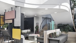 A modern lobby with a curved ceiling, a staircase, and seating areas. - B&B HOTEL Lyon Centre Part-Dieu Gambetta (Lyon)