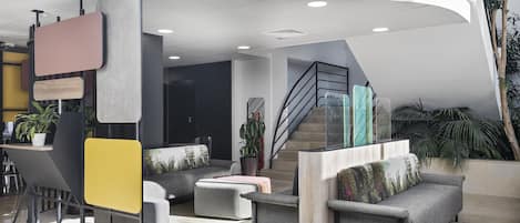 A modern lobby with a curved ceiling, a staircase, and seating areas.