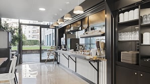 A modern kitchen with a bar area, equipped with various appliances and a glass display case. - B&B HOTEL Lyon Centre Part-Dieu Gambetta (Lyon)