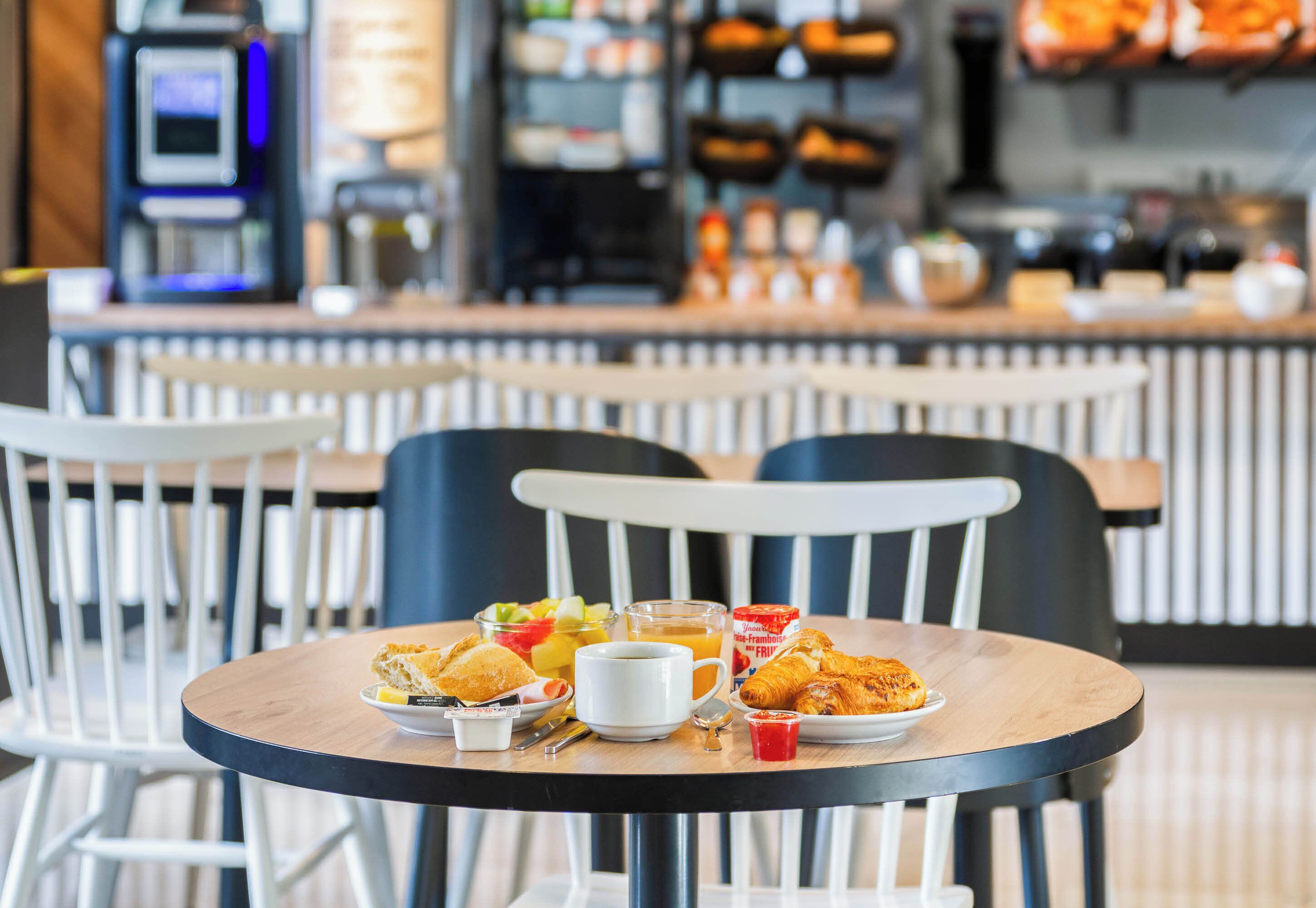 A breakfast table with croissants, fruit, juice, and coffee.