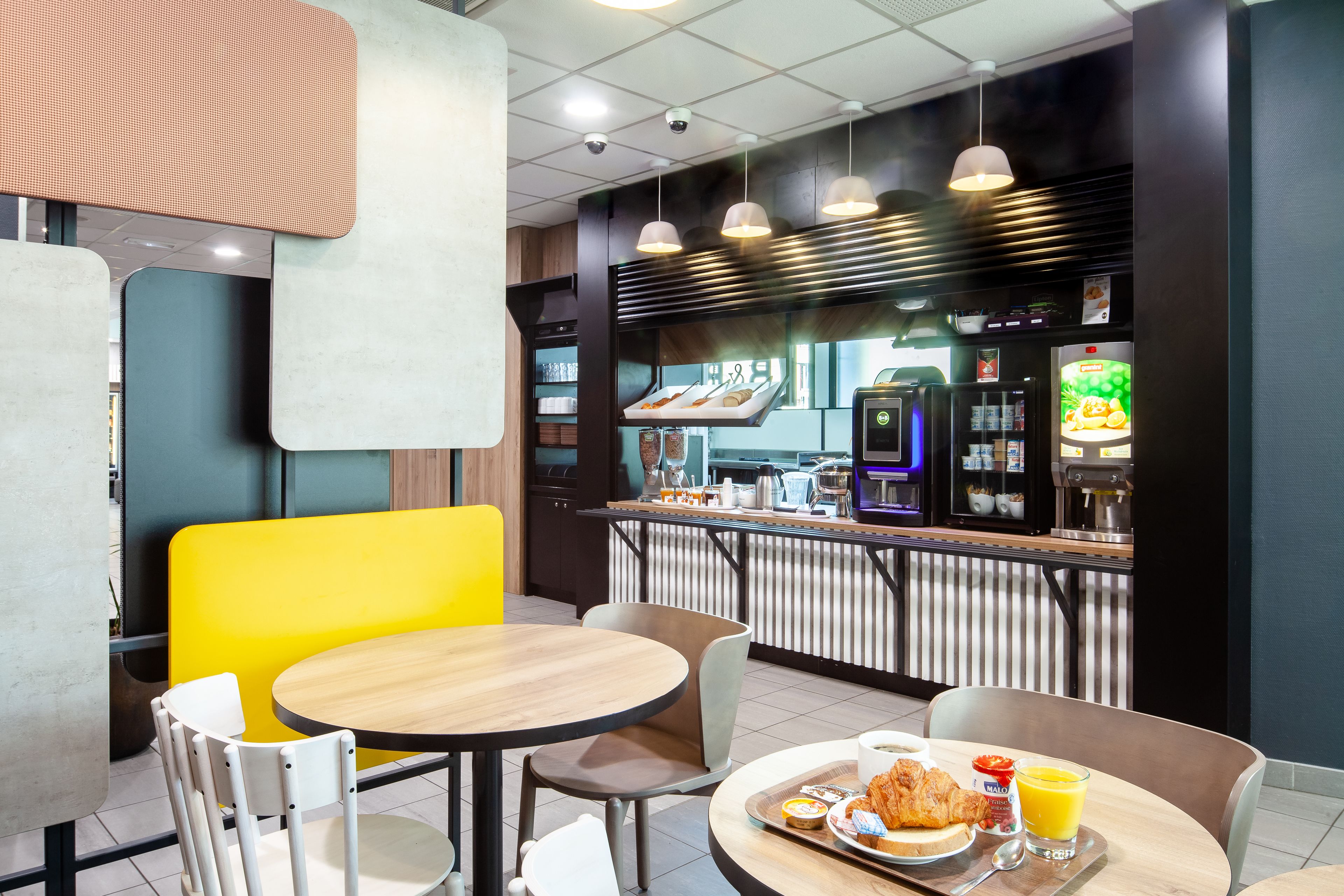 A modern cafe with a counter, seating area, and a variety of food and drink options.