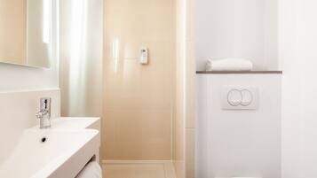 A modern bathroom with a sink, mirror, and shower area.