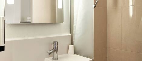 A bathroom with a white sink, a mirror, and a shower curtain.