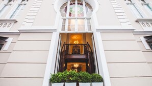 A building facade with a large arched window, a staircase leading to an upper level, and a small garden area in front. - Curitiba Palace Estação (Curitiba)