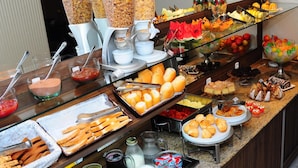 Ein Buffet mit verschiedenen Speisen, darunter Obst, Gebäck und Getränke.