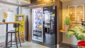 Un hall d’hôtel équipé d’un distributeur automatique, d’un réfrigérateur et d’un espace détente.