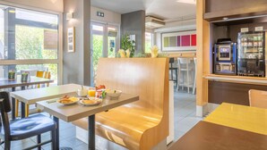 Un intérieur de restaurant moderne, avec des tables et des chaises, un appareil à café et un tableau affichant le menu.