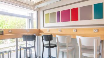 A modern interior with a bar area, bar stools, and a wall with colorful panels.