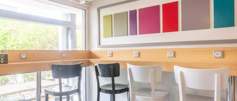 A modern interior with a bar area, bar stools, and a wall with colorful panels.