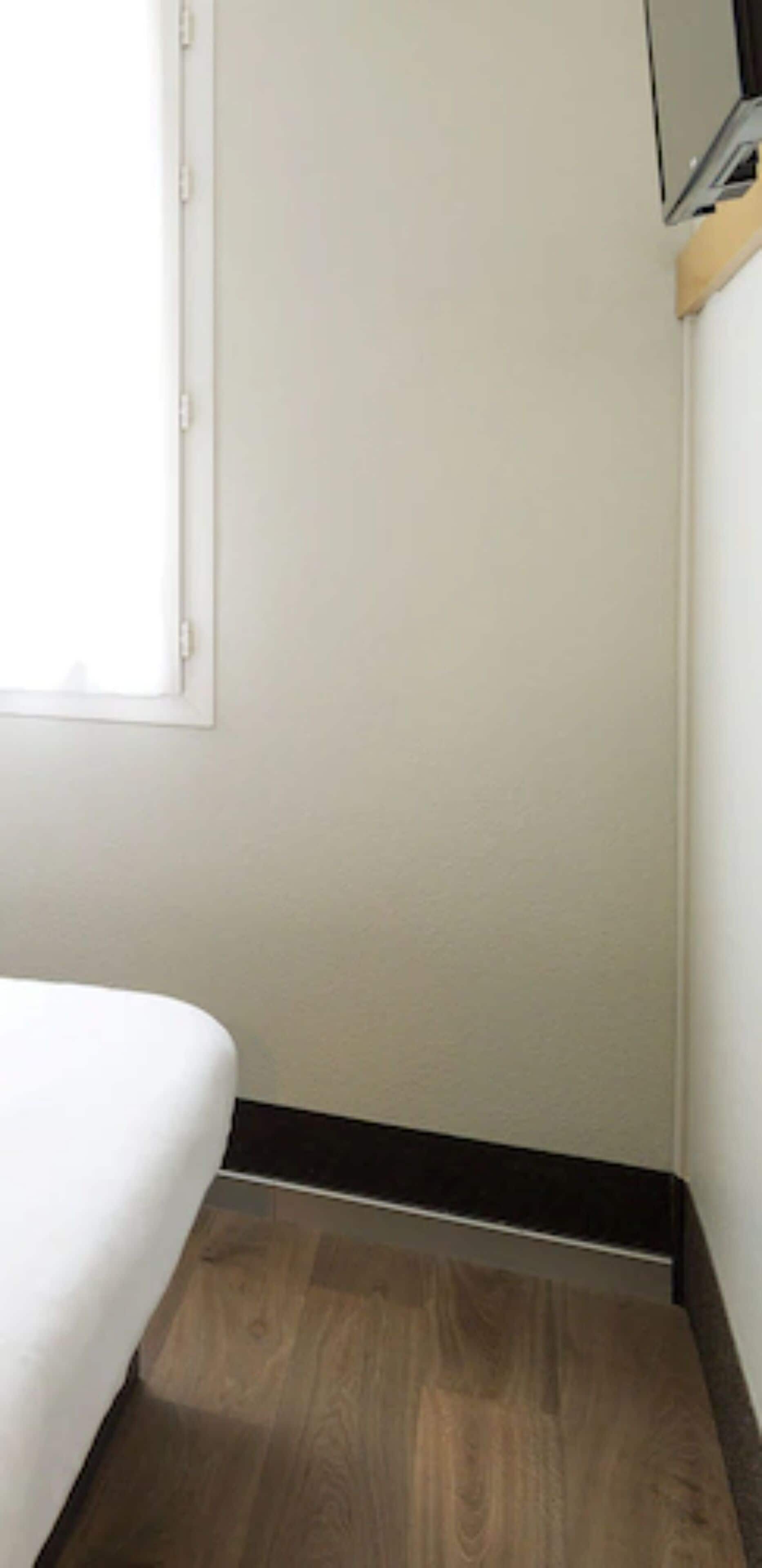 A room with a bed, a window, and a wooden floor.