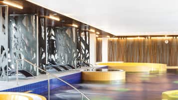 Een binnenzwembad, ligstoelen bij het zwembad