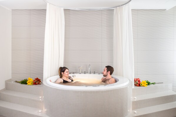 A modern bathroom with a large freestanding bathtub, tiled walls, and a shower curtain. - Estonia Resort Hotel & Spa (Parnu)
