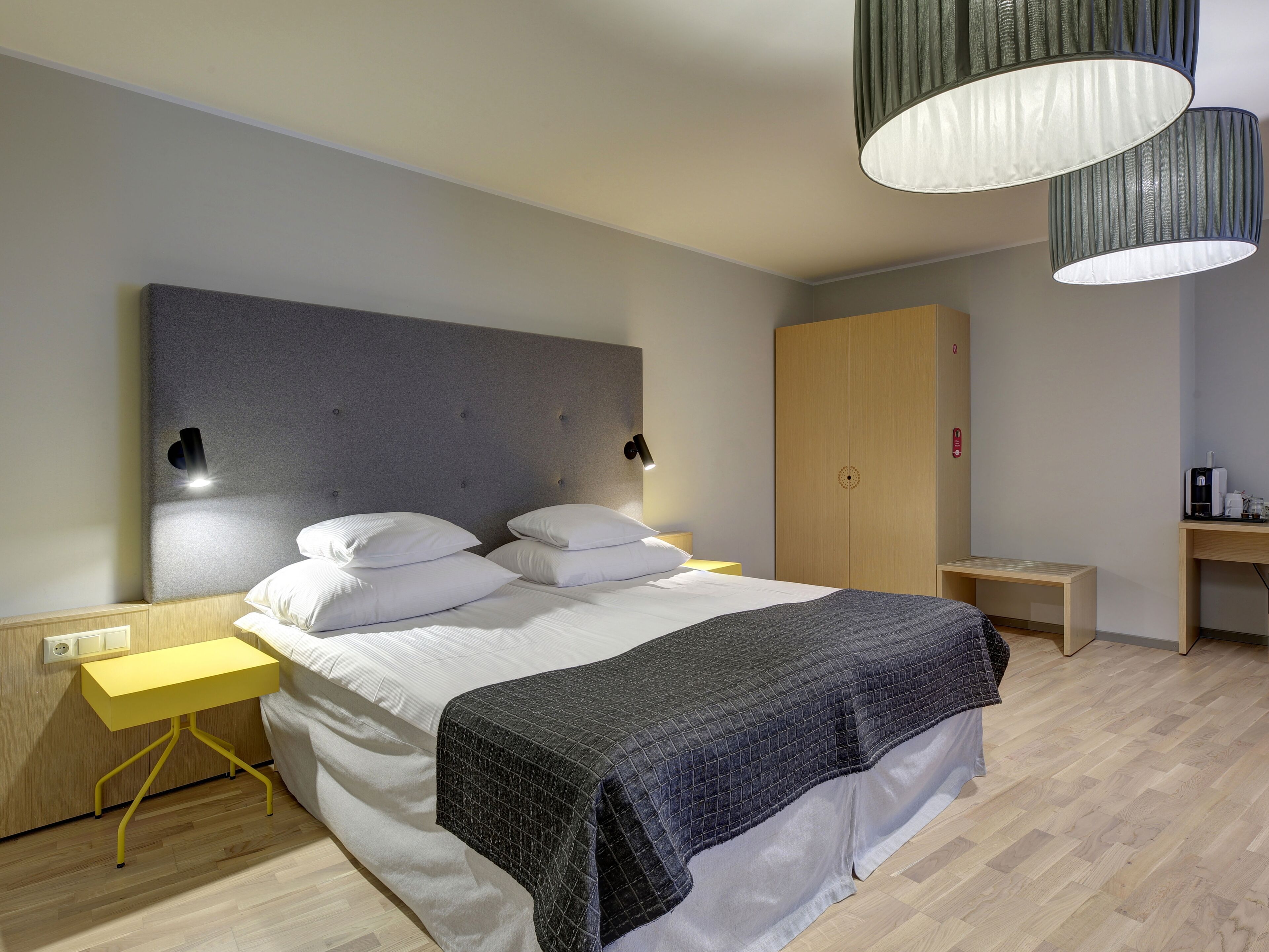 A modern bedroom with a bed, bedside tables, a wardrobe, and a desk with a lamp.