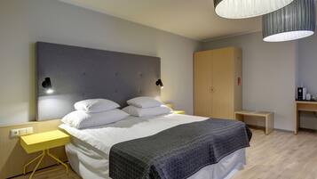 A modern bedroom with a bed, bedside tables, a wardrobe, and a desk with a lamp.