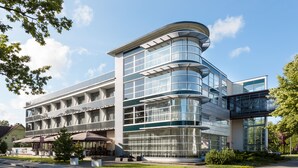 A modern building with a curved glass facade, multiple floors, and a covered outdoor seating area. - Estonia Resort Hotel & Spa (Parnu)