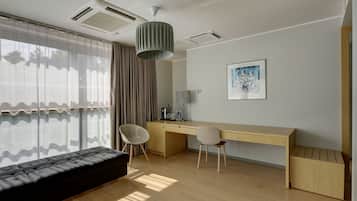 A modern room with a wooden desk, two chairs, a bench, and a ceiling fan.