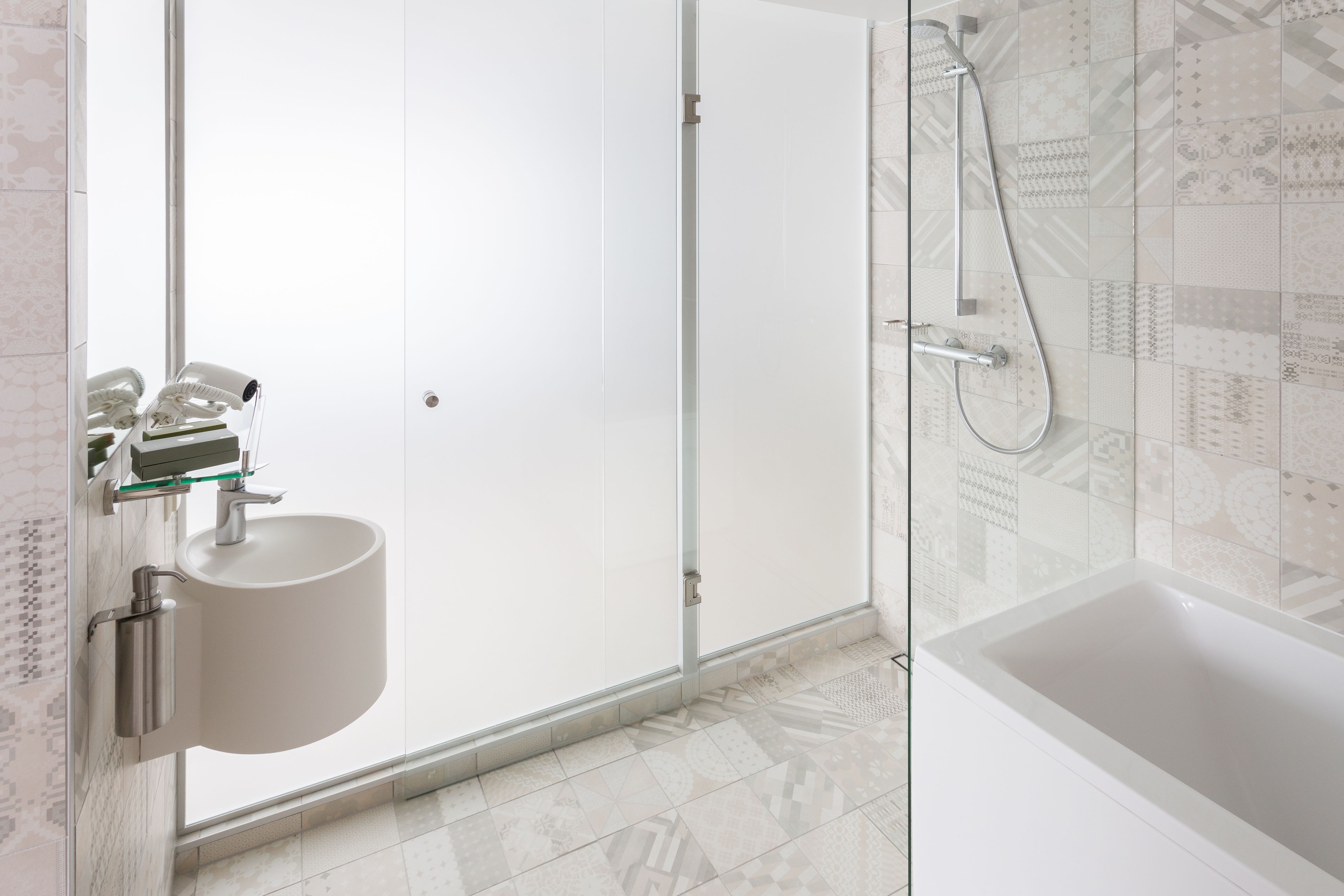 A modern bathroom with a glass shower enclosure, a white sink, and a bathtub.