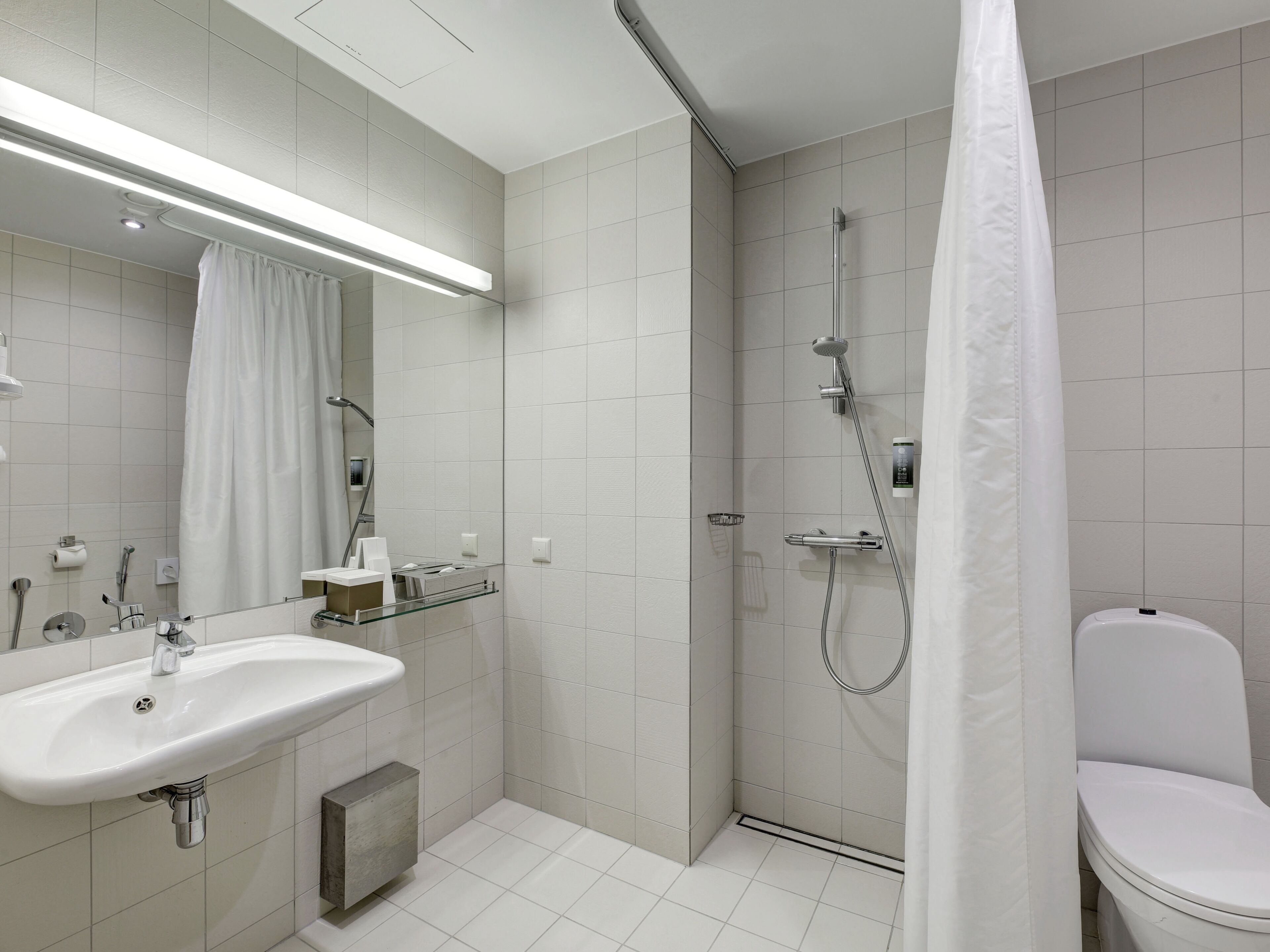 A modern bathroom with a shower, toilet, and sink.