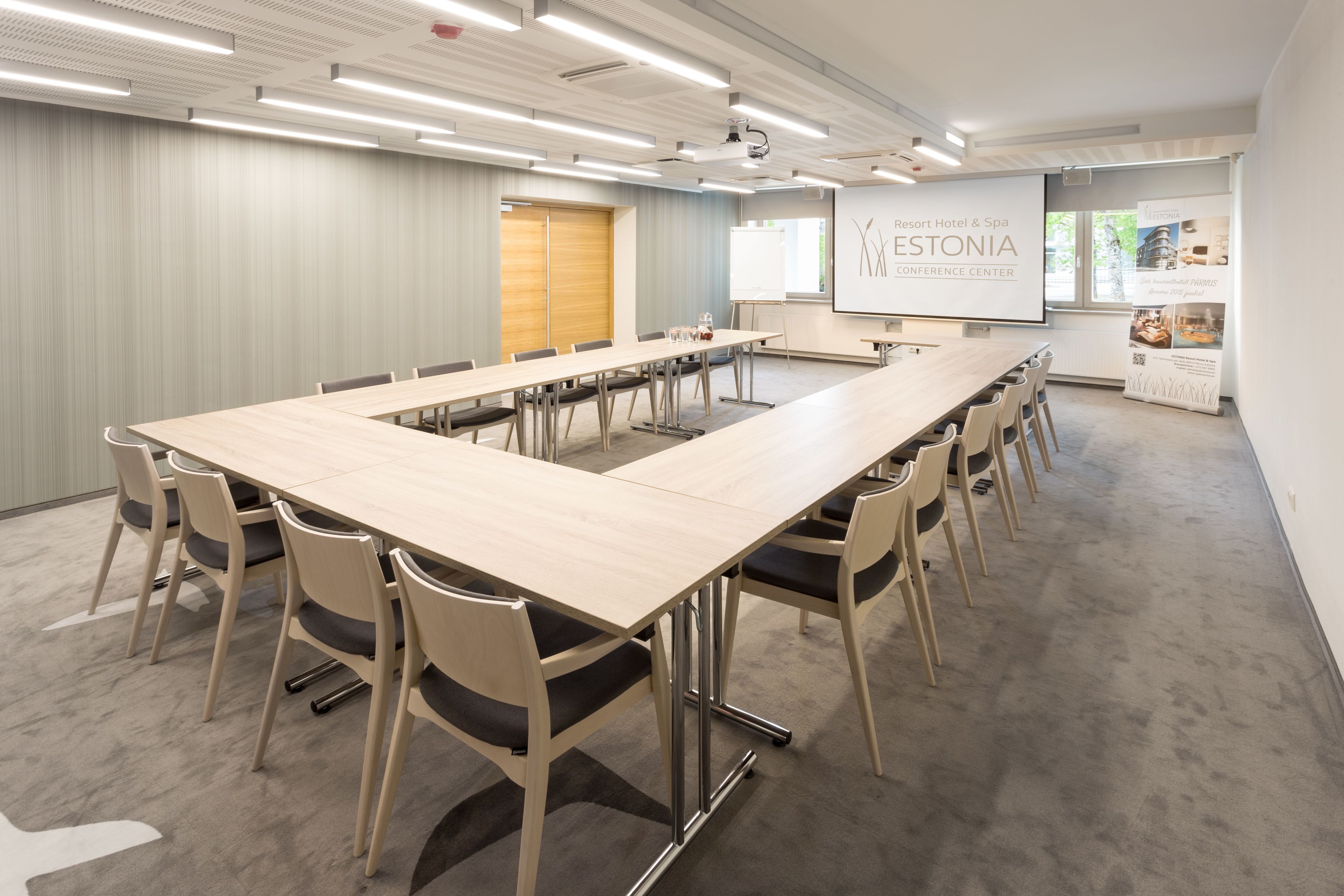 Una sala conferenze con un lungo tavolo, sedie, uno schermo per proiettore e una lavagna per presentazioni.