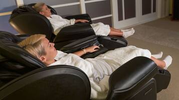 Two massage chairs in a room with a neutral color scheme and a door in the background.