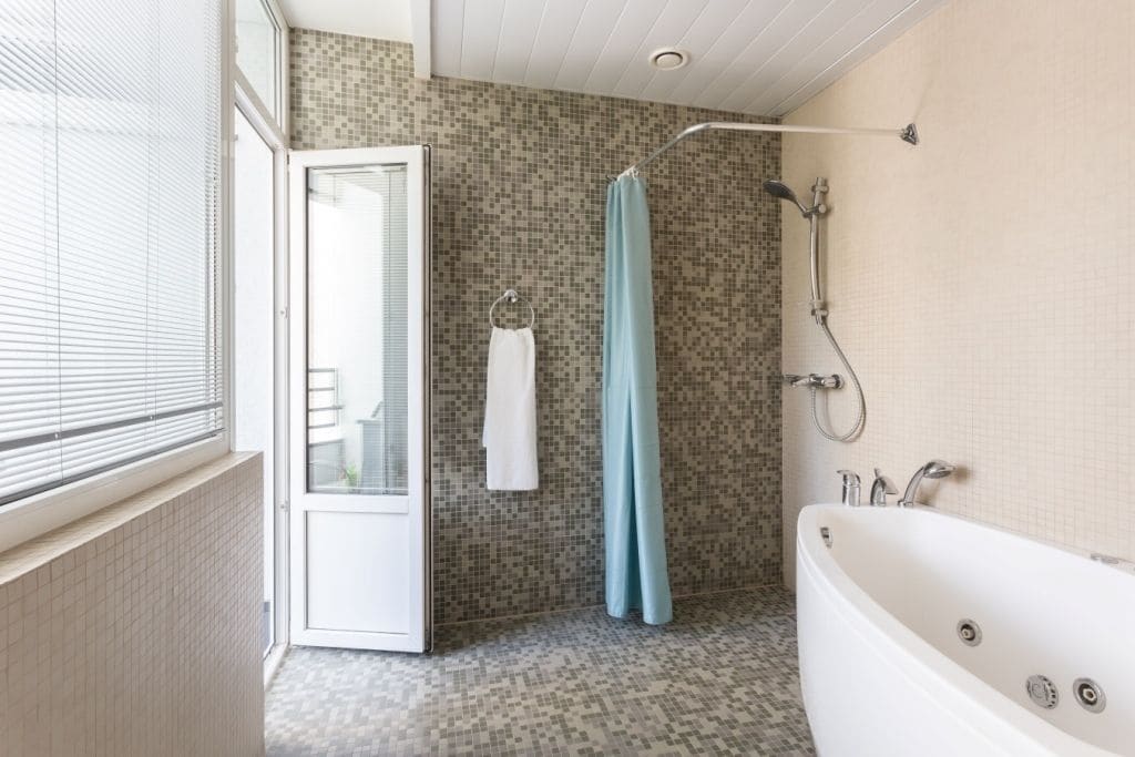A bathroom with a shower, a bathtub, and a glass door leading to a balcony.