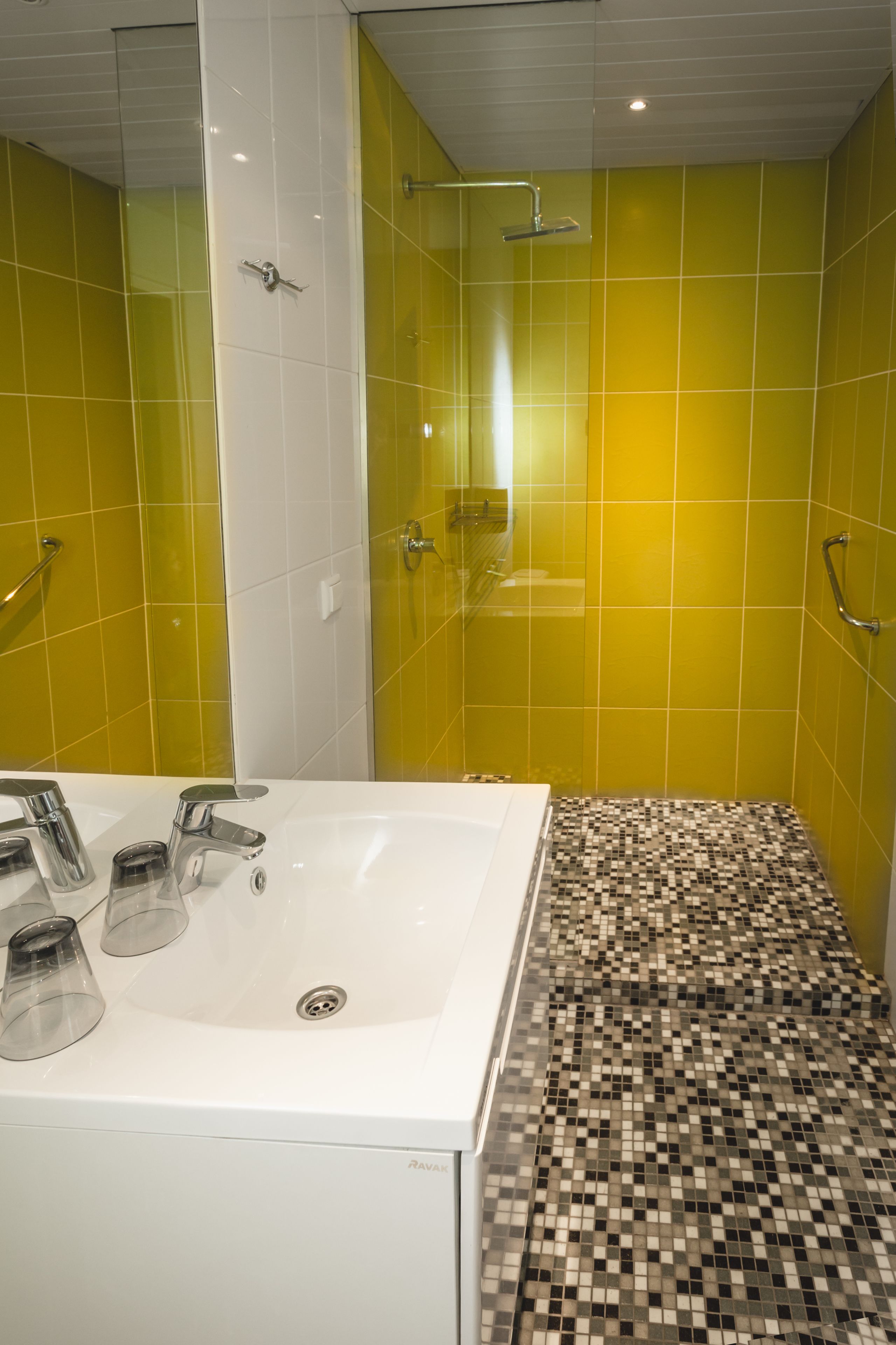 A bathroom with yellow tiles, a white sink, and a shower area.