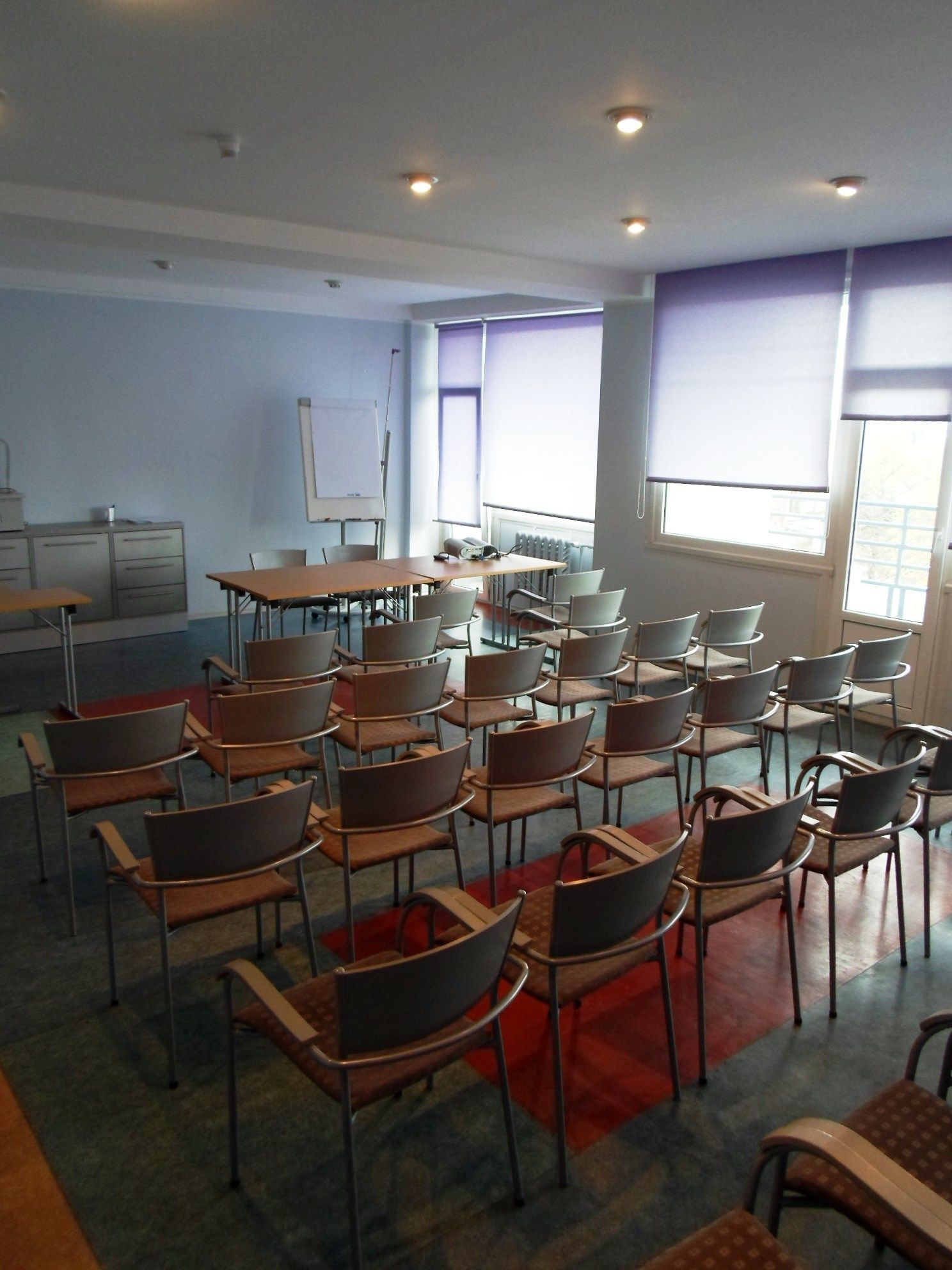 Ein Klassenzimmer mit Reihen von Stühlen, einer Tafel und einem Fenster mit Jalousien.