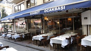 An outdoor dining area with tables and chairs, a blue awning with the text "SOHBET OCAKBASI", and a glass storefront. - Grand Hisar Hotel (Istanbul)