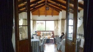 A cozy room with a wooden ceiling, a sofa, a dining table, and chairs. - Posada del Angel (Colonia del Sacramento)