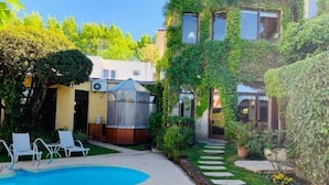 A backyard with a swimming pool, a greenhouse, and a garden path. - Posada del Angel (Colonia del Sacramento)