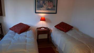 A bedroom with two beds, a nightstand, a lamp, and a framed picture on the wall.
