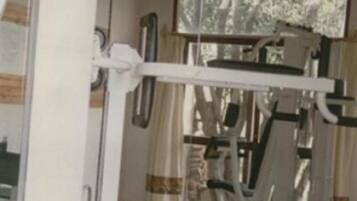 A gym with exercise equipment, a window with curtains, and a wooden floor.