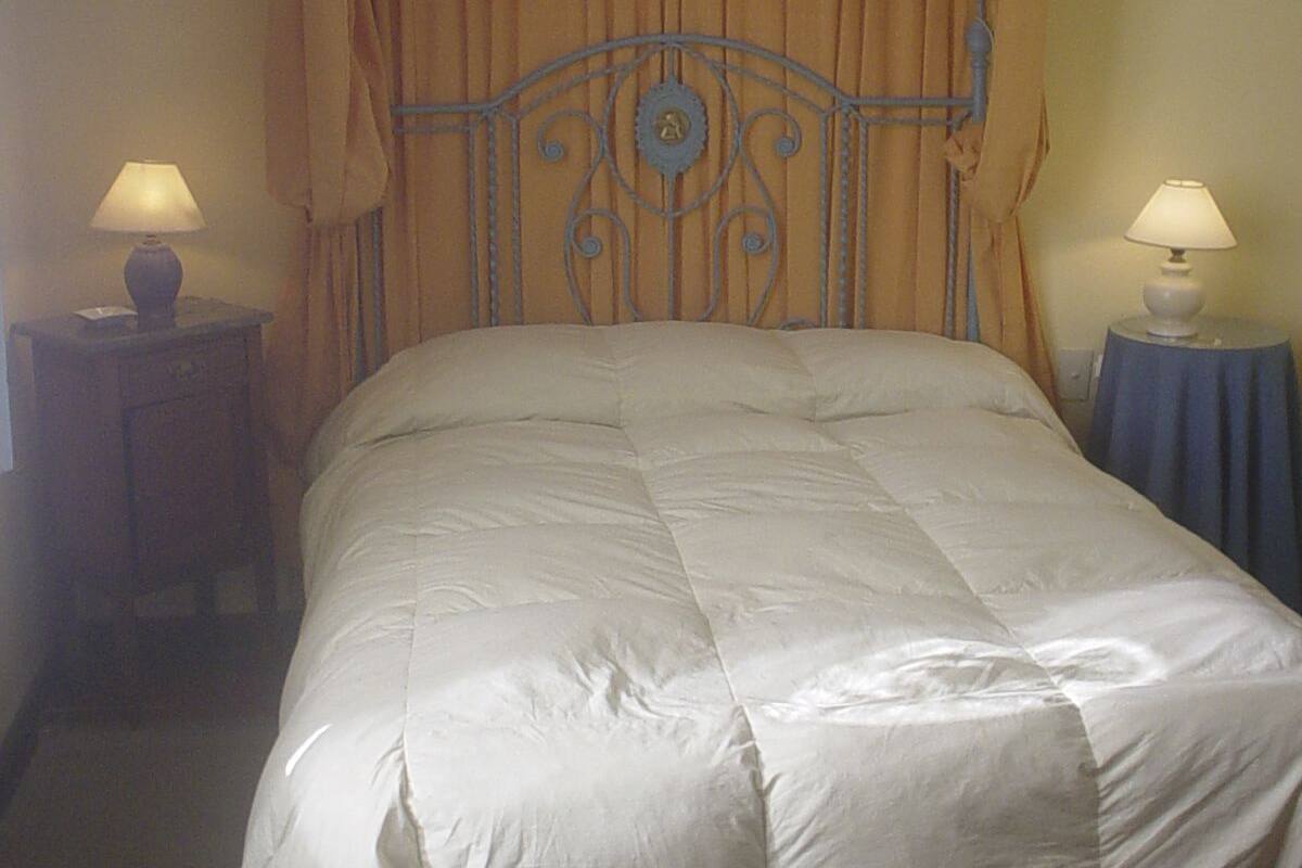 A bed with a headboard, two bedside tables with lamps, and curtains.