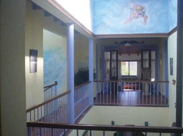 A spacious interior with a balcony, a staircase, and a mural on the ceiling. - Posada del Angel (Colonia del Sacramento)