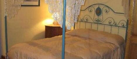 A bed with a metal headboard and a lace canopy.