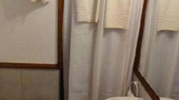 Een badkamer met een houten toilet, een witte wastafel en een douchegordijn.