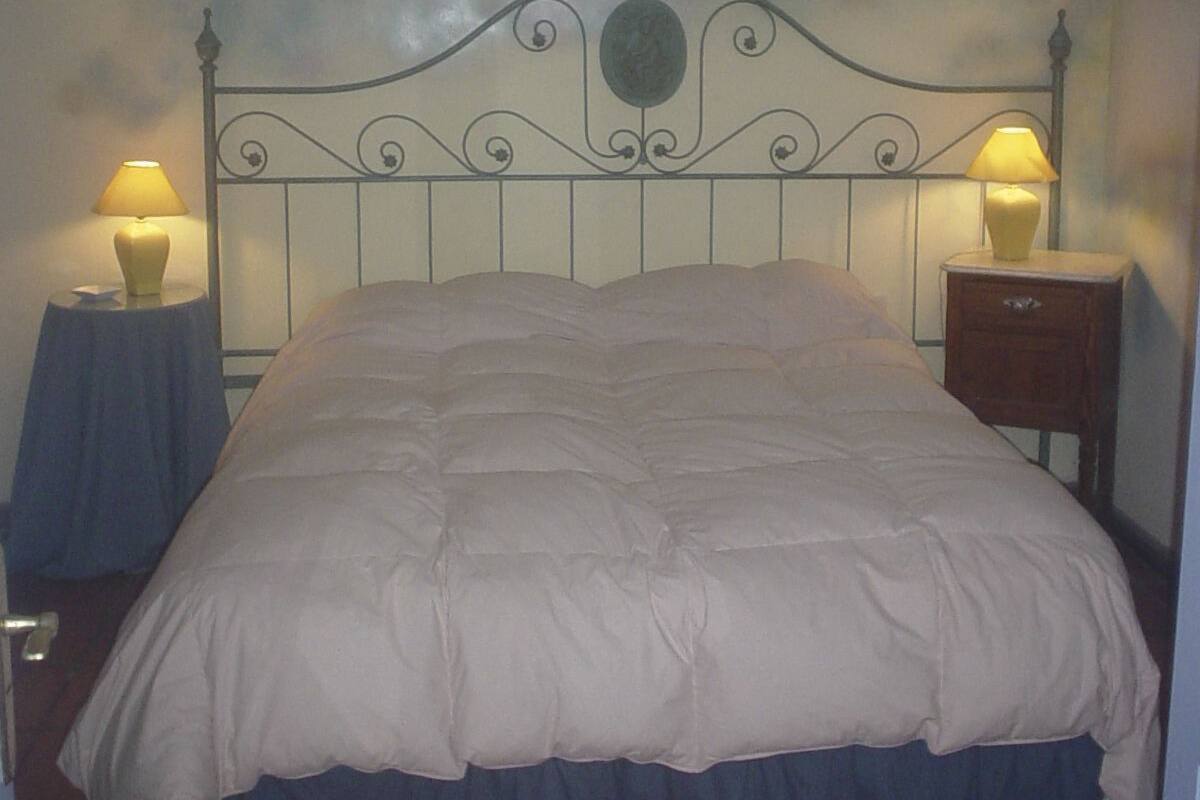 A bed with a metal headboard, two bedside tables with lamps, and a mural on the wall.