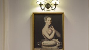 Une pièce dans laquelle on peut voir un portrait encadré d’une femme, une machine à café et une table avec des tasses et des soucoupes.