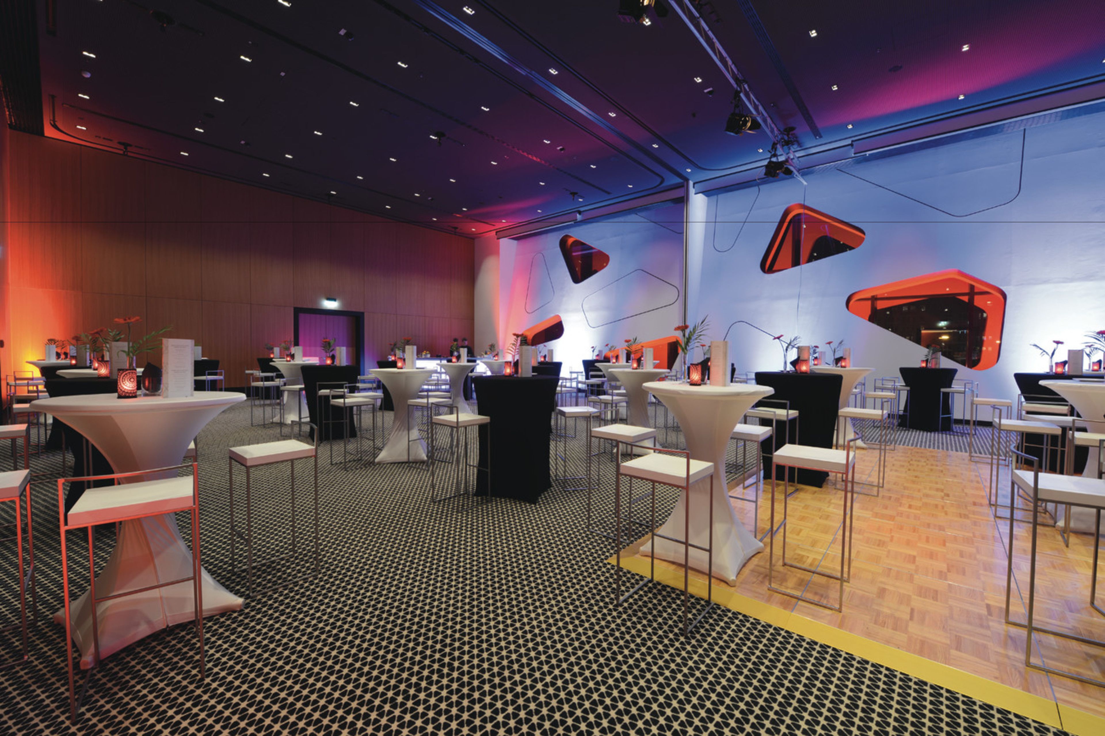 A modern conference room with round tables, black and white chairs, and a patterned floor.