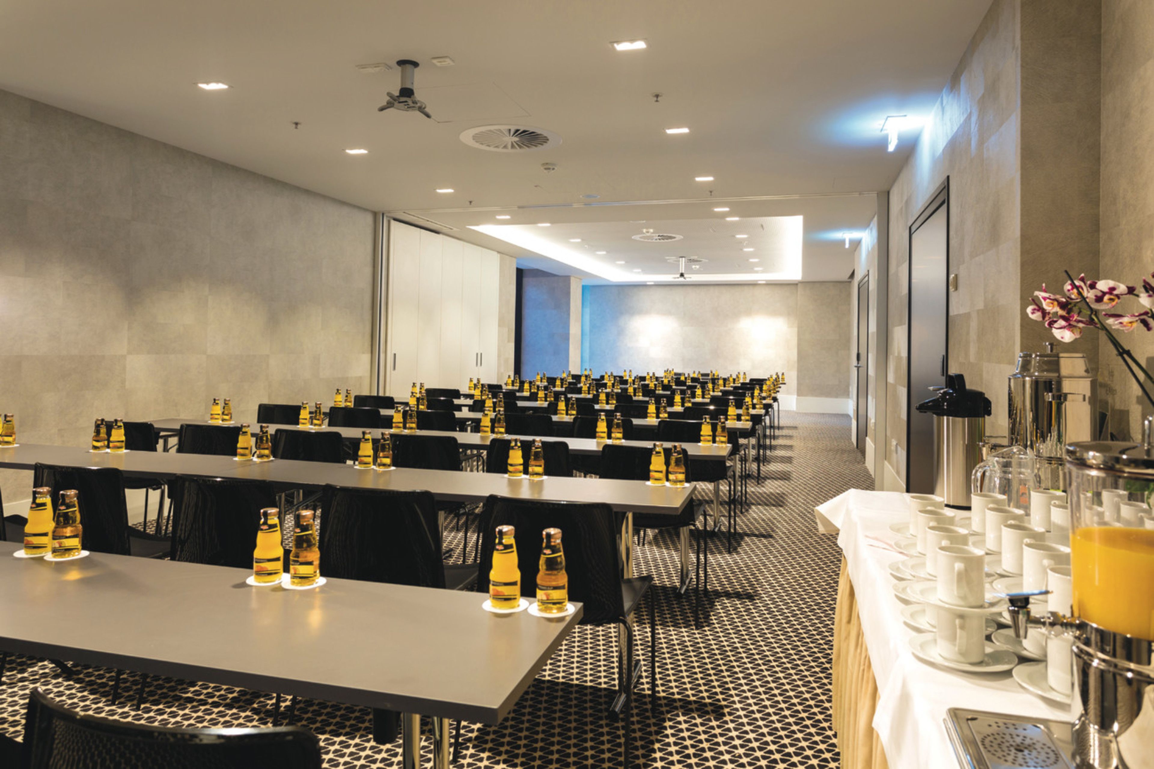 Una sala conferenze con lunghe tavolate, sedie e un'area buffet con cibo e bevande.