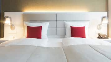 Ein Hotelzimmer mit einem großen Bett, zwei roten Kissen, weißer Bettwäsche und zwei Nachttischlampen.