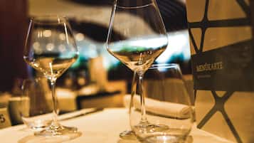 Dos copas de vino sobre una mesa, con un atril de menú al fondo.