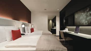 Une chambre d’hôtel moderne avec deux lits, un bureau et une télévision.